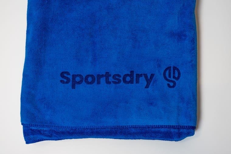 Nærbillede af Sportsdry-logoet broderet på det blå håndklæde