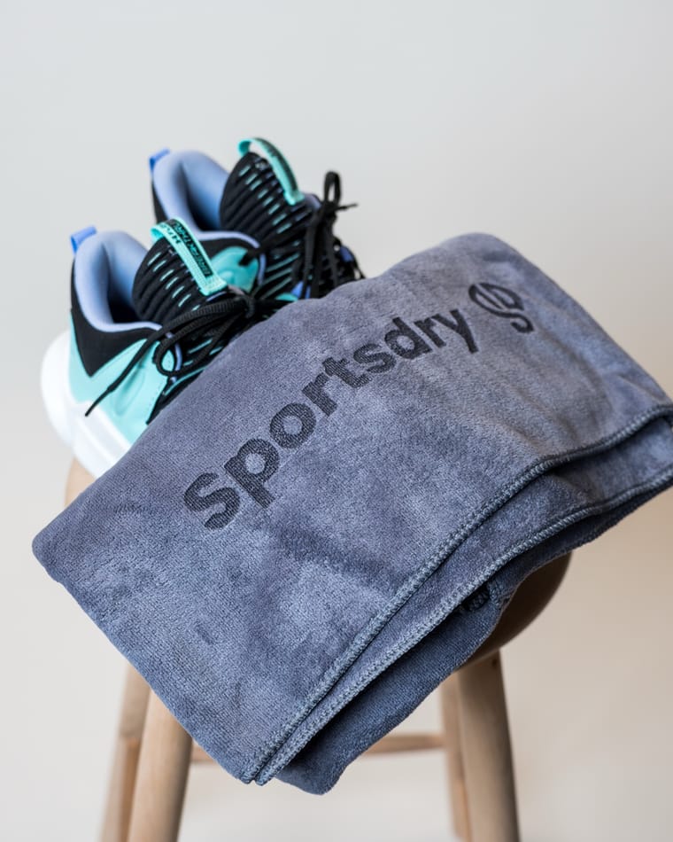 Gråt håndklæde lagt over en skammel ved siden af et par sneakers
