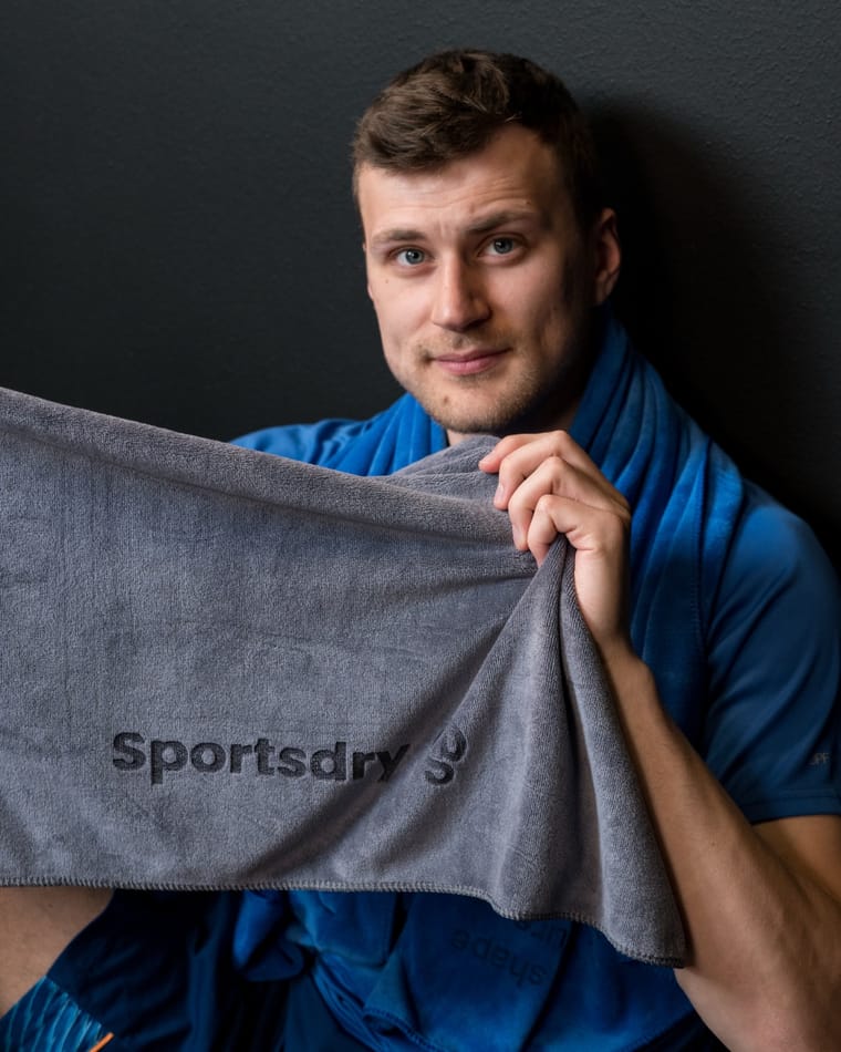 Nærbillede af Sportsdry-logoet på det grå håndklæde mod mørk baggrund